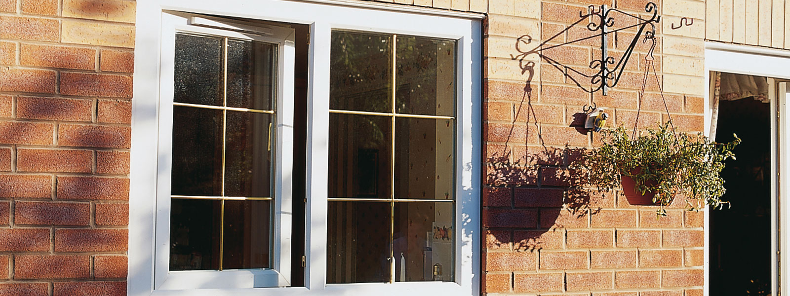 View of a tilt-turn window installation, showcasing a modern design. The window is positioned open in a tilt mode, allowing for ventilation while maintaining security. The frame features a sleek finish, blending seamlessly with the surrounding wall.